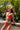 Woman in a colorful bikini and straw hat posing against a tropical background.