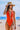 Person in an orange swimsuit and straw hat at the beach