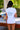 Back view of a person wearing a white t-shirt with a tropical design and the text 'Tell Only Your Best Friends'.