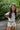 Woman in casual summer outfit with sunglasses, standing in a garden setting.