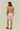 A man with curly hair wearing pink patterned swim trunks and black sandals, standing with his back to the camera.