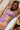 A woman in a purple bikini relaxing on a sun lounger, wearing sunglasses.
