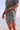 Man in a green leopard print outfit standing by the water