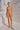 Person wearing an orange bikini standing against a white rocky background.