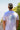 A person wearing a white t-shirt with a palm tree graphic and the text 'Tell Only Your Best Friends' on the back, standing outdoors.