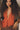Person wearing a red textured garment with a deep neckline and relaxed pose