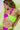 A woman wears a vibrant two-tone bikini with pink and green colors, accessorized with a beaded necklace.