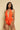 Model wearing an orange textured swimsuit with a deep neckline and bow detail.