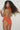 Person with curly hair wearing an orange backless swimsuit