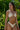 A person posing in a white bikini amidst tropical greenery.