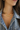 Close-up of a person wearing a gold necklace with a heart pendant, set against a denim jacket.