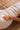 Close-up of a person lying on a wooden surface, wearing a white textured garment with a hand resting on their waist.