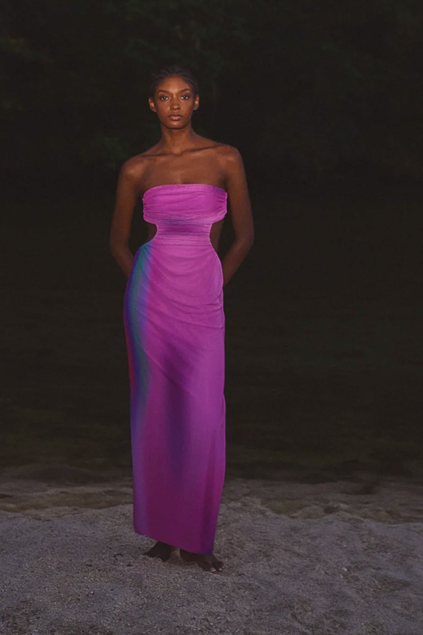 Person wearing a strapless purple dress in a dark outdoor setting.