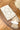 Beige and white patterned pouch with tassels on wooden surface