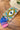 Colorful clutch with eye design and tassels on wooden surface