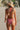 Woman in a red and white checkered bikini and straw hat on a beach.