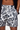 Person wearing white shorts with black abstract pattern on a plain background