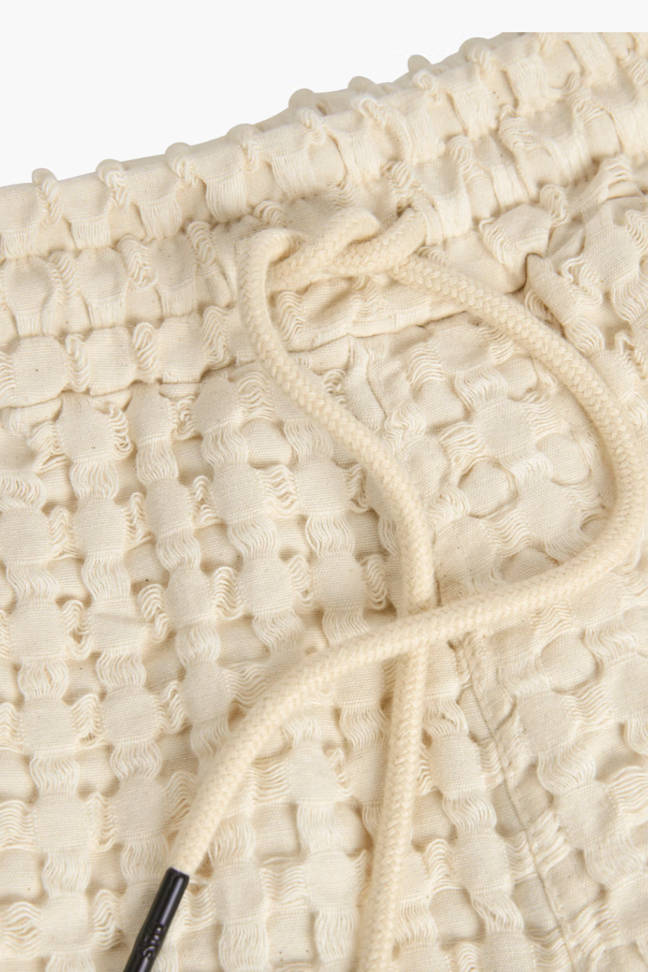 Close-up of textured white fabric with a rope detail