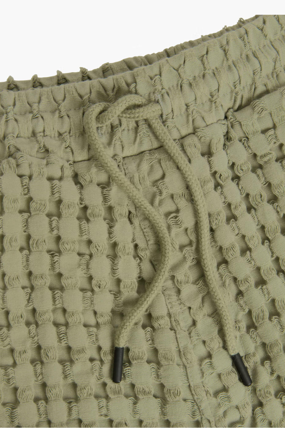 Close-up of a textured green shorts with a drawstring.