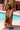 Person wearing a colorful floral and leopard print skirt by a poolside.