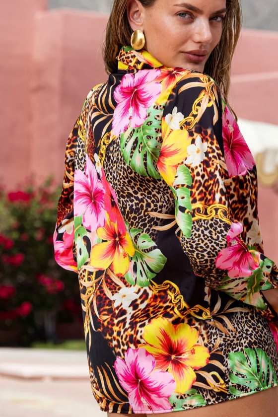 Woman wearing a colorful floral and animal print dress by a poolside.