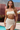 Woman in a beige bikini standing by a pool with a desert landscape in the background