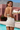 Woman in a white dress standing by a pool with mountains in the background