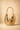 Woven handbag with bamboo handle and colorful keychain on a beige background